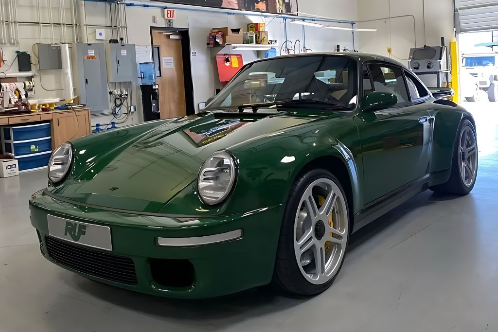 A green Ruf sports car parked in a well-lit garage, showcasing its glossy exterior, which is likely protected by a paint protection film.